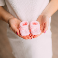Baby booties in the hands of a pregnant mother.