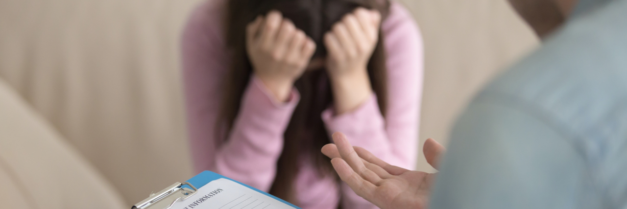 Hundreds Affected After Freezer Malfunctions at Two Fertility Clinics Young lady sitting on the couch opposite to doctor and crying. Male doctor holding clipboard.