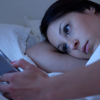 young woman lying in bed on social media at night