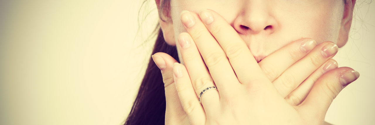 woman covering mouth with hands close up