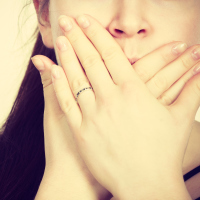woman covering mouth with hands close up