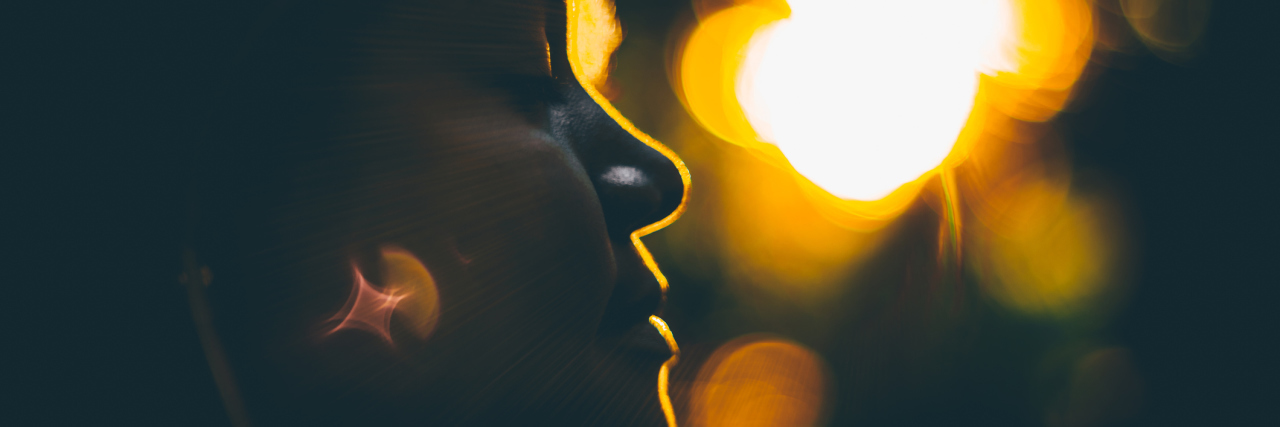 Why Accepting Your Illness Doesn't Mean Giving Up True tilt-shift side view silhouette of lady backlighted by stunning orange sunset with strong bokeh and chroma hoop, with copy space place for text, logo or your advertising