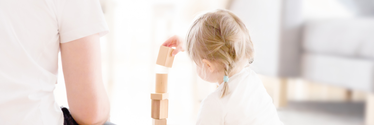 To the Parents Wondering What I'm Thinking in Early Intervention Cute girl playing with wooden blocks ont he floor with her father