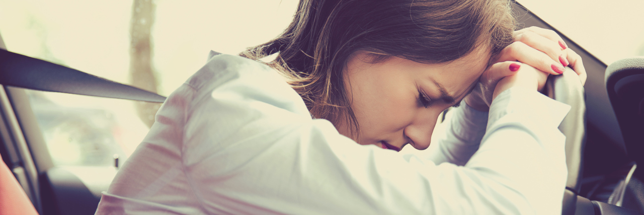Why Anxiety Makes My Ordinary Days Exhausting tired woman in car leaning against steering wheel