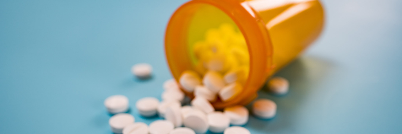 I'm Medicated for My Mental Illness — and I’m OK With That Pile of white pills on blue background