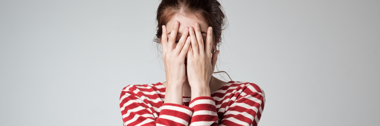 Embarrassing Spoonie Moments woman wearing a red and white striped shirt covering her face with her hands