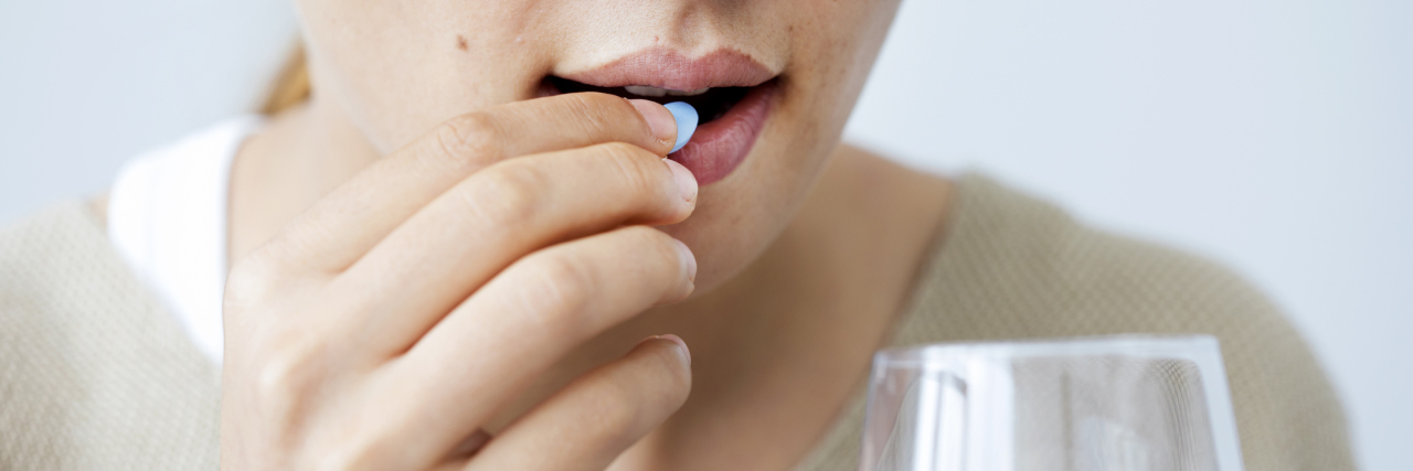 Realizing How Much Medication Helps Me With Chronic Pain woman taking a pill and holding a glass of water