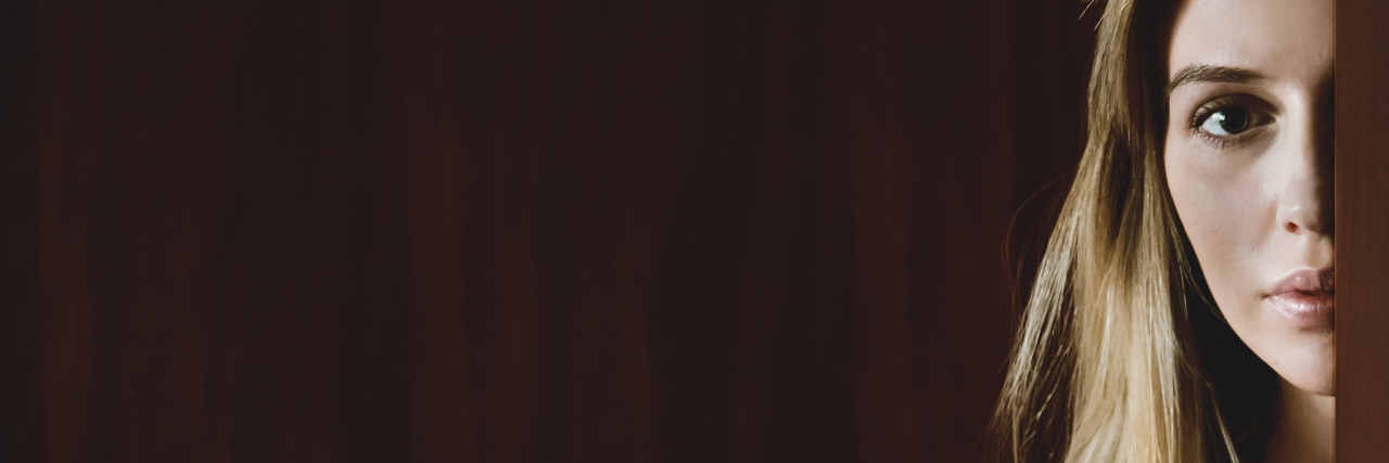 The Reality of Living With Invisible Illness woman peeking out from behind a door
