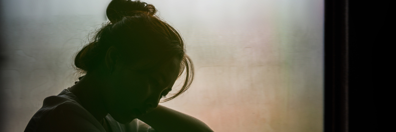 Experiencing Flashbacks as a Childhood Sexual Assault Survivor Vintage filtered on silhouette of depressed girl sitting on the window