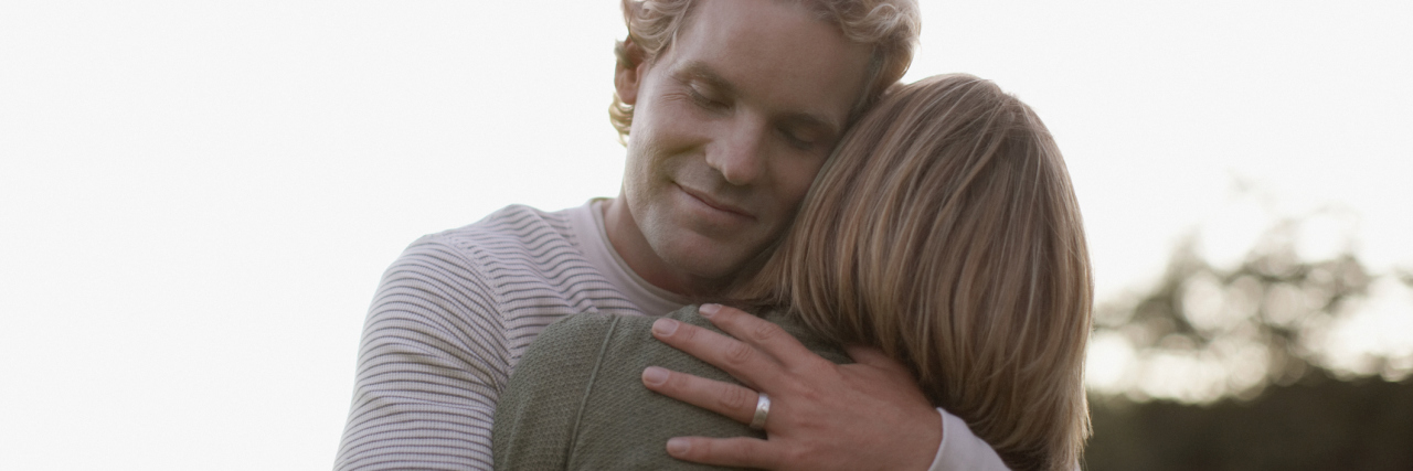 Why You Shouldn't Tell Your Husband He Can Leave Because You're Sick husband hugging and holding his wife while standing outside