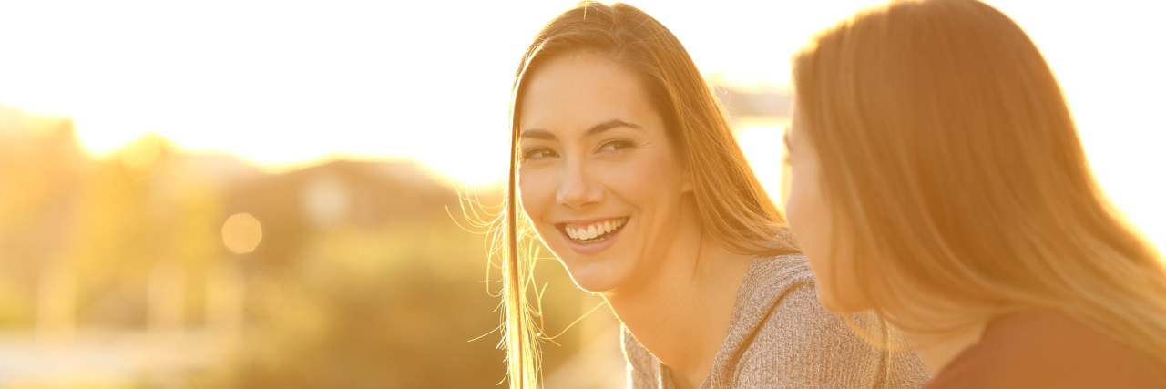 What a 'Comfort Person' Means to Someone With Anxiety Two happy friends talking outside in a house balcony at sunset