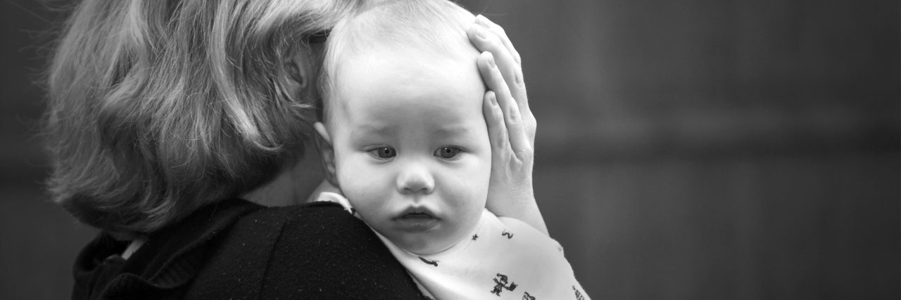 Parenting a Child With Bladder Exstrophy Mother comforting a sad baby in black and white