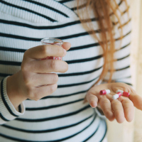 young redhead woman holding pills in hand and cup