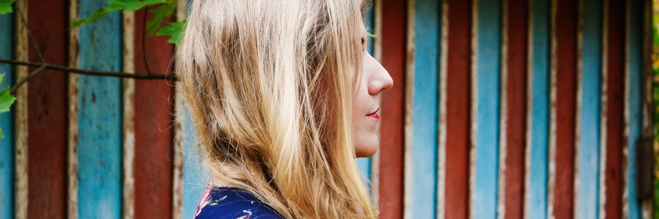 woman with blonde hair standing in front of a red and blue striped building