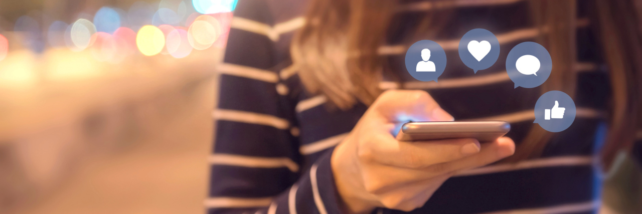 The Positive Role of Social Media With Chronic Illness woman standing outside and using her cell phone with social media icons surrounding it