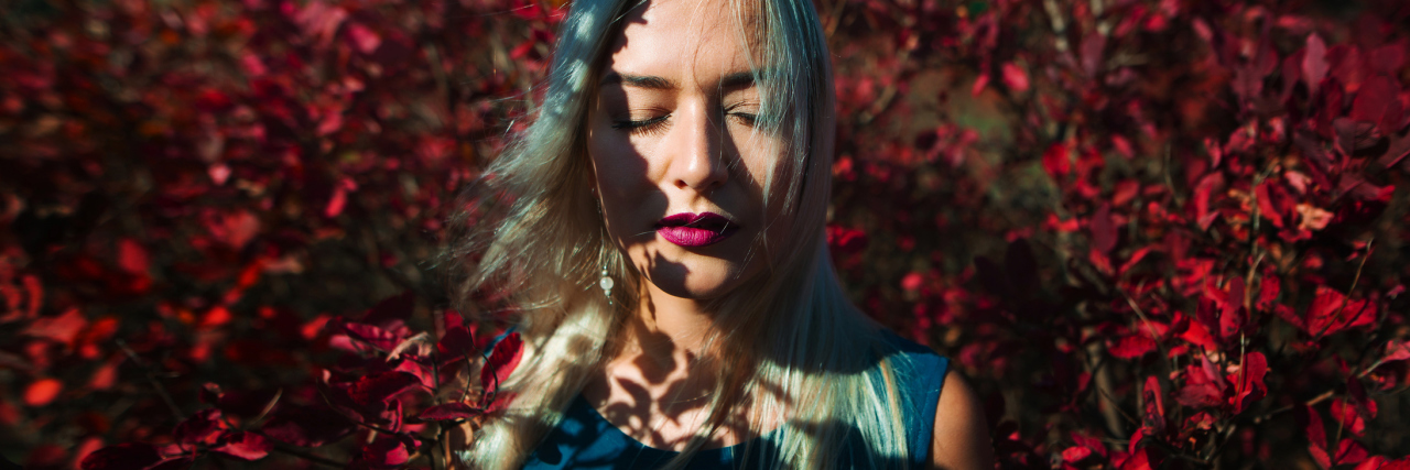 Feeling Jealous of Healthy People During a Chronic Illness Flare-Up woman standing in front of red leaves