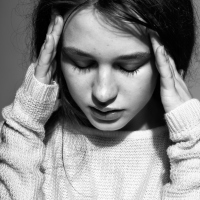 young woman in white pullover sweater against gray background looking depressed or upset