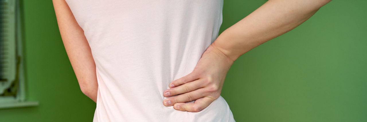 10 Things I've Learned After Living With Back Pain for 15 Years A woman holding her back.