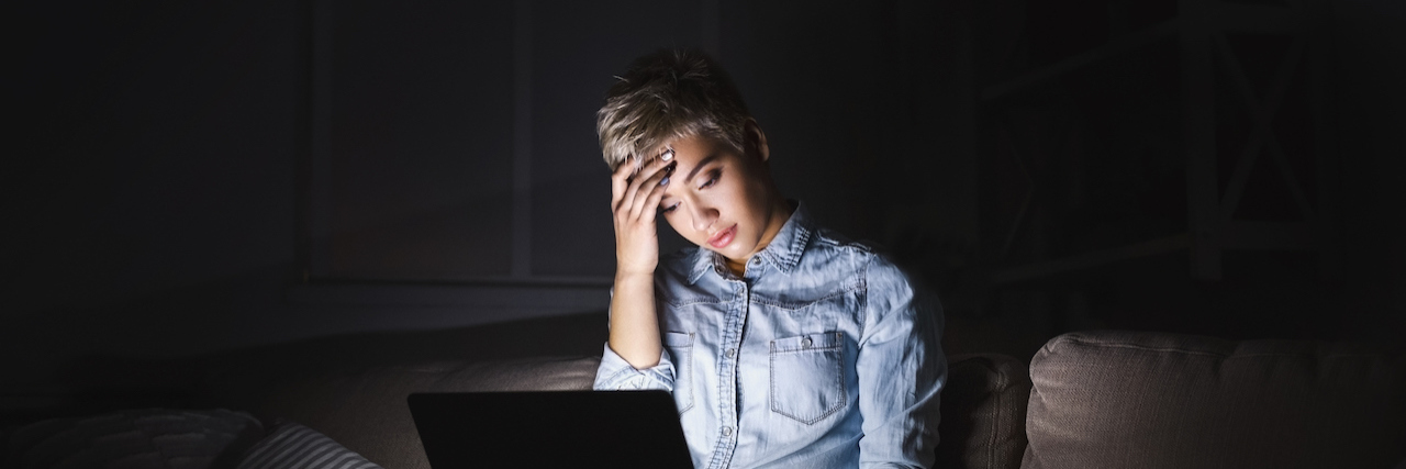 Living With PTSD in the Age of #MeToo A woman sitting in the dark looking at her computer screen