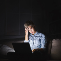 A woman sitting in the dark looking at her computer screen