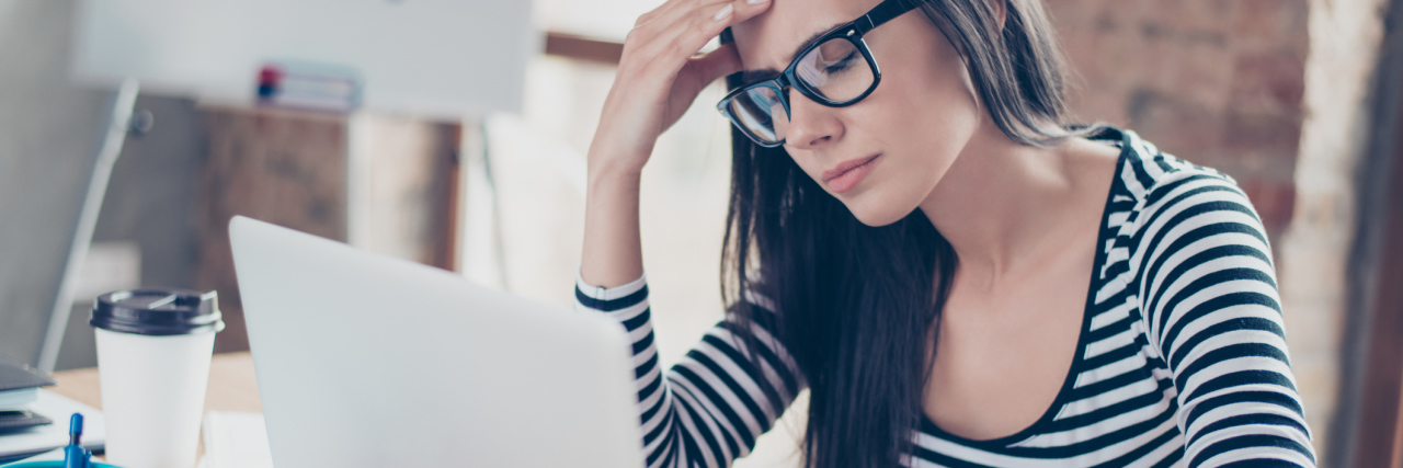 How I Wish I'd Helped My Colleague With His Mental Health tired stressed businesswoman sitting at table in front of laptop