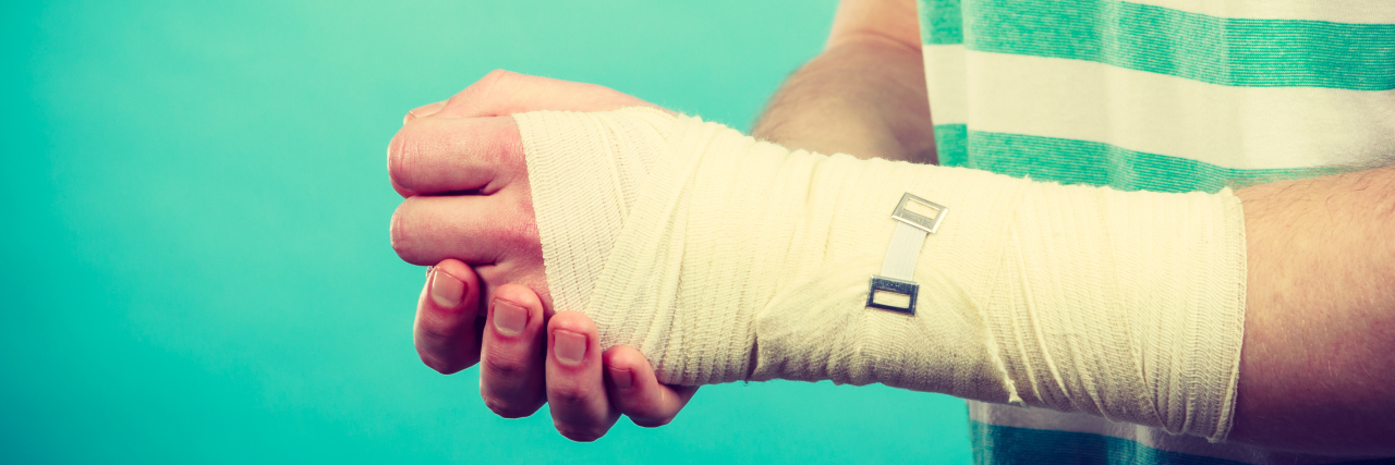 Autism and Pain Perception Young man holds bandaged hand.