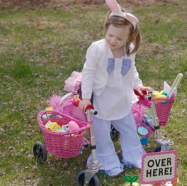 Little girls using walker, wearing bunny ears and two pink baskets and on the sides of the wakler