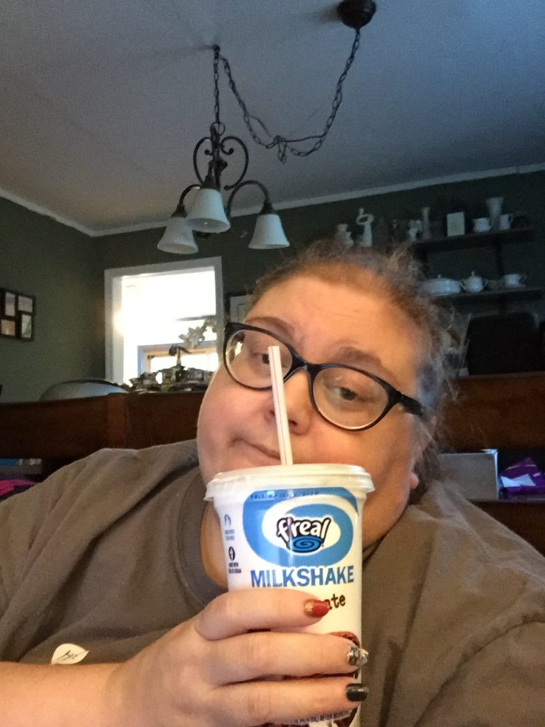 woman sitting in bed and drinking a milkshake