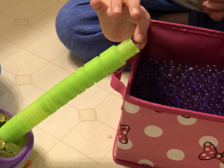 Practicing fine motor skills, beads in tube