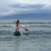 woman paddleboarding through waves in the ocean