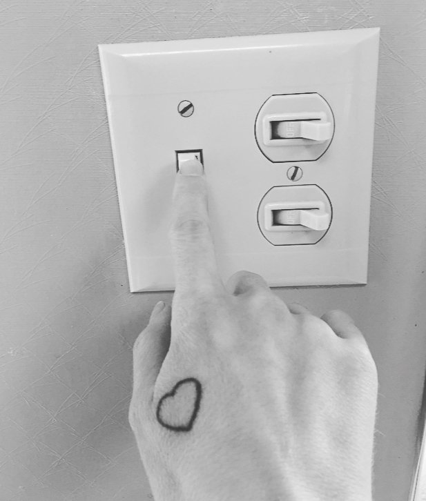 woman with heart tattoo on her hand flipping a light switch