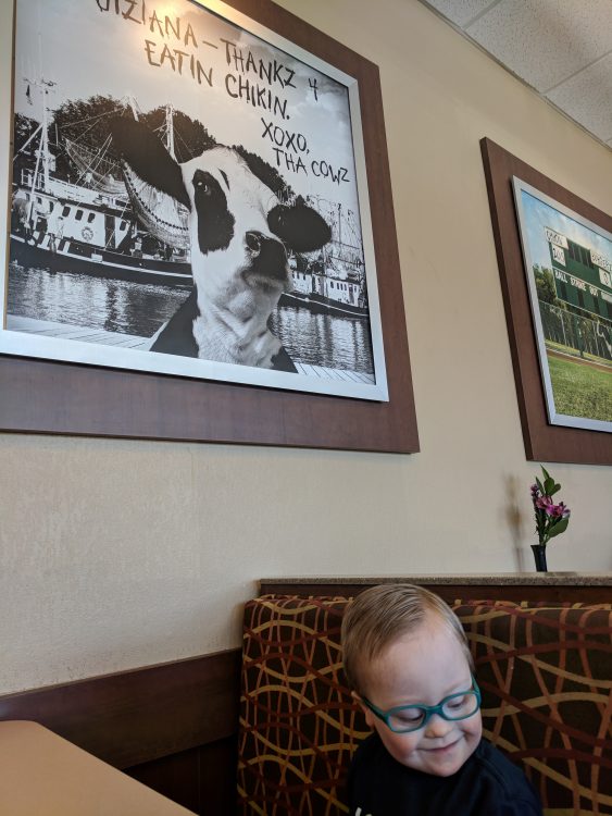 Little boy with down syndrome and cow poster above