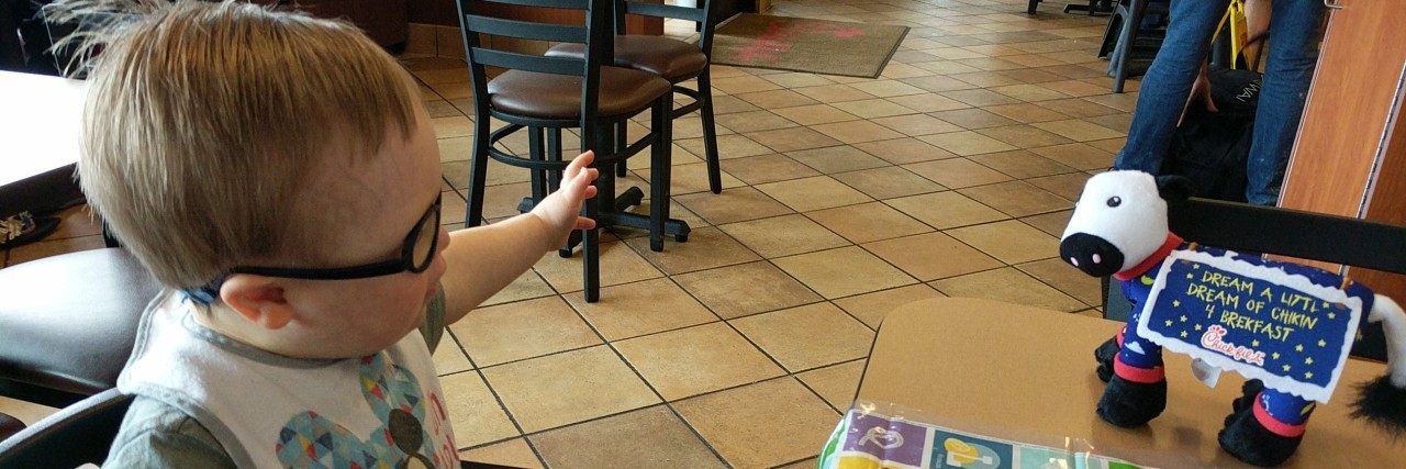 My First Conversation With My 2-Year-Old Son With Down Syndrome Little boy with Down syndrome looking at cow toy at Chick-Fil-A