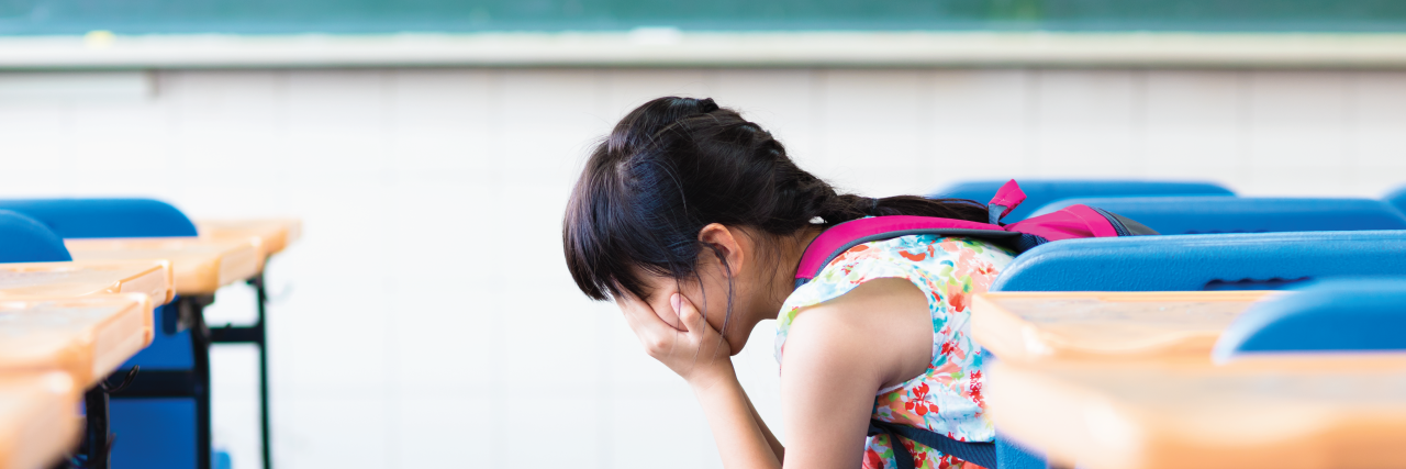 23 'Harmless' Comments Teachers Said That Hurt Their Students' Mental Health small girl in classroom with face in hands