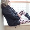 woman in a black coat, rainboots and pink leggings sitting on a window ledge