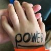 Hand with little pinky bent a little. On the hand with black marker the word: power