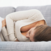 woman lying on the couch holding her abdomen
