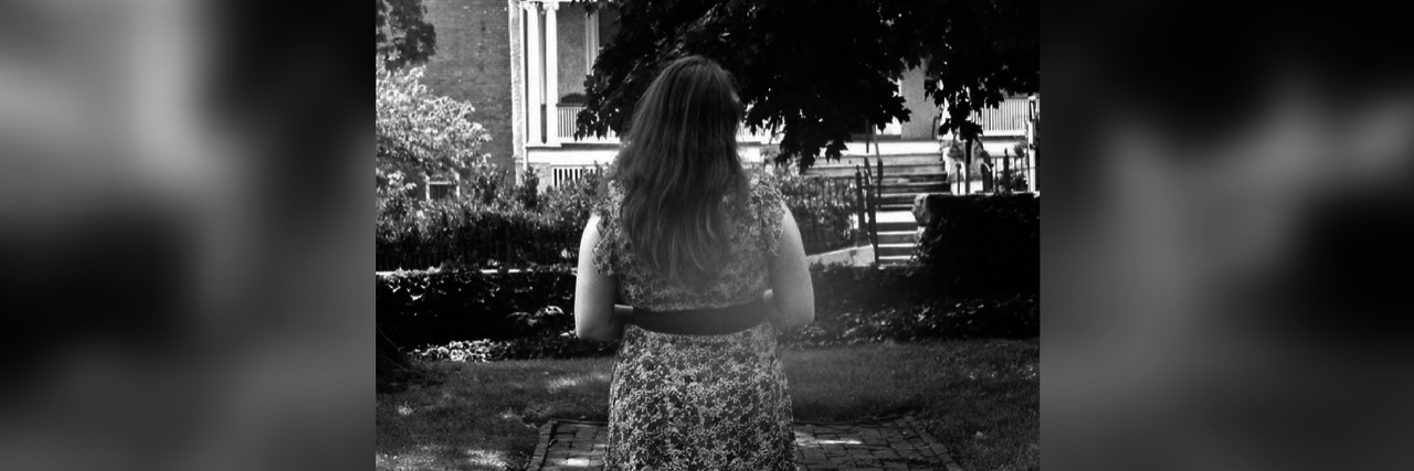 black and white photo of a woman in a dress walking outside