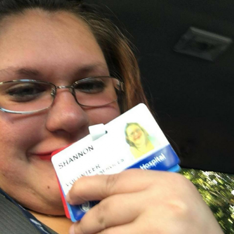 woman smiling and holding a hospital volunteer badge