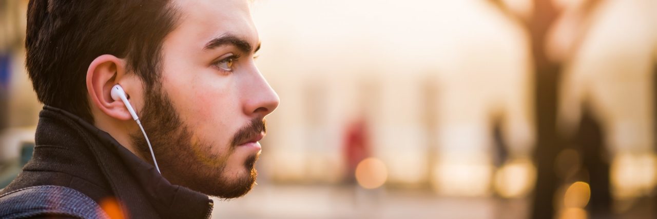 How to Define Depression If You Struggle to Define It young bearded man against blurred background with earphones in his ears looking into distance