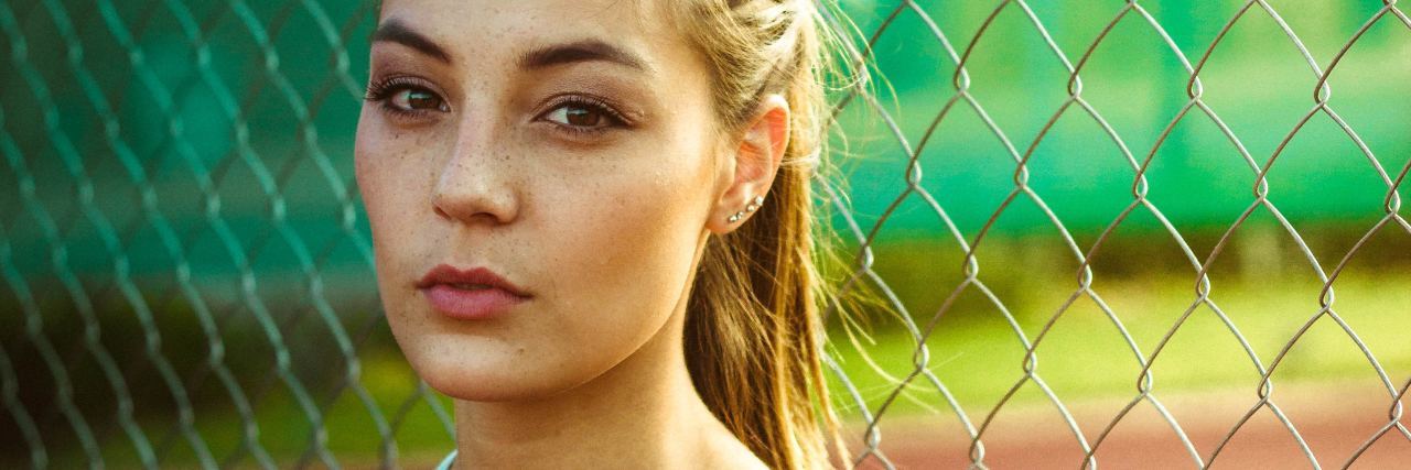 What You Might Not Know About My 'High-Functioning' Anxiety a woman with a ponytail standing in front of a fence