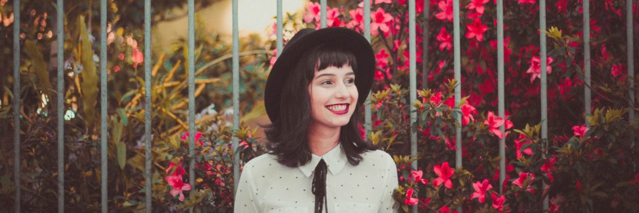 How to Function Well With Severe Mental Illness woman smiling in front of gate with flowers