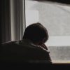 man looking out window in dark room alone depression