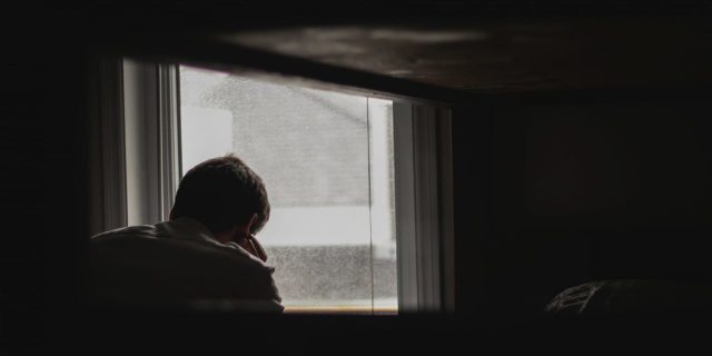 The Real Reason Asking for Help Is Hard When You Have Depression man looking out window in dark room alone depression