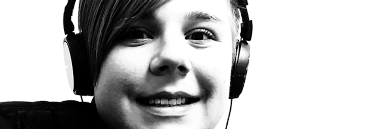 Black and white image of close up face boy wearing headphones smiling at camera