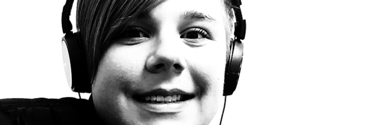 Helping My Son on the Autism Spectrum Find His Voice Black and white image of close up face boy wearing headphones smiling at camera