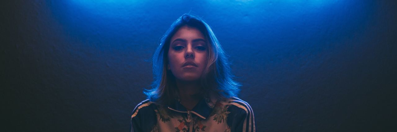 Why Having 'Dark' Thoughts Doesn't Make You a Bad Person woman in front of neon sign