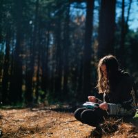 girl in the woods looking at a notebook