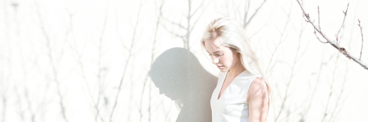 Where I've Found Hope in My Struggle With Bipolar Disorder a woman with blonde hair stands outside with shadows of trees surrounding her