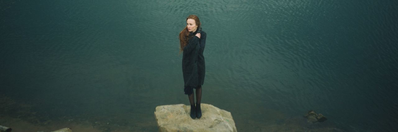 10 Things I Never Want to Be Told When I'm Struggling With Anxiety woman stands on rock surrounded by water